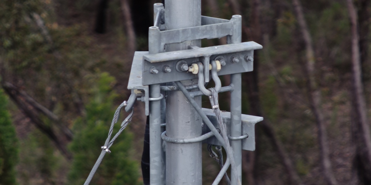 Close inspection photograph of a steel connection, with individual bolts, cable strands and fasteners visible
